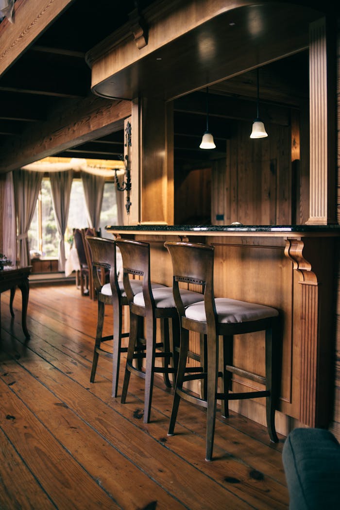 Warm and inviting rustic interior featuring a wooden bar and chairs with natural lighting.